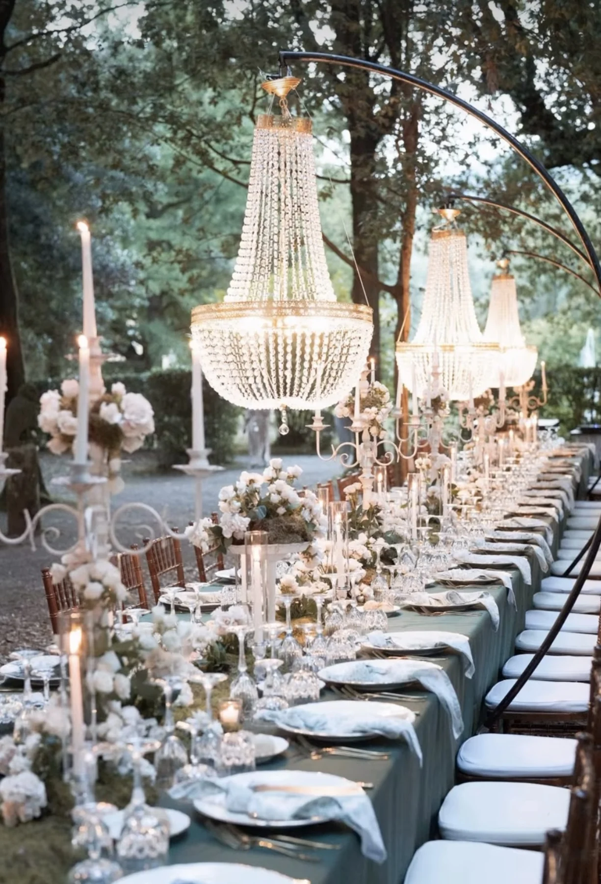Lampadari sopra una tavola elegante tra gli alberi